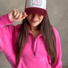 Front view of model wearing the Breast Cancer Gear: You Can Do It Trucker Hat that has a burgundy bill and back, a snapback, pink trim, and a cream front with an embroidered pink and burgundy graphic. 