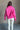 Back view of model wearing the Hot Pink Quarter-Zip Sweatshirt that has hot pink knit fabric with a soft fleece interior, long raglan sleeves, a quarter-zip front with a high neck, and a kangaroo pocket.