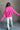 Back view of model wearing the Hot Pink Quarter-Zip Sweatshirt that has hot pink knit fabric with a soft fleece interior, long raglan sleeves, a quarter-zip front with a high neck, and a kangaroo pocket.