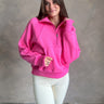 Front view of model wearing the Hot Pink Quarter-Zip Sweatshirt that has hot pink knit fabric with a soft fleece interior, long raglan sleeves, a quarter-zip front with a high neck, and a kangaroo pocket.
