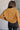 Back view of model wearing the Nicole Brown Cropped Long Sleeve Sweatshirt which features light brown cotton fabric, a cropped waist, a round neckline and long sleeves.