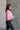 Side view of model wearing the Catherine Pink Heathered Mock Neck Sweater that has pink and white heather knit fabric, ribbed hem, a high neck, and long balloon sleeves with cuffs.