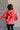 Back view of model wearing the Lauren Washed Red Zip-Up Hoodie Sweatshirt that has two pockets, a silver zipper, a hood with drawstrings, dropped shoulders, and long sleeves with cuffs.
