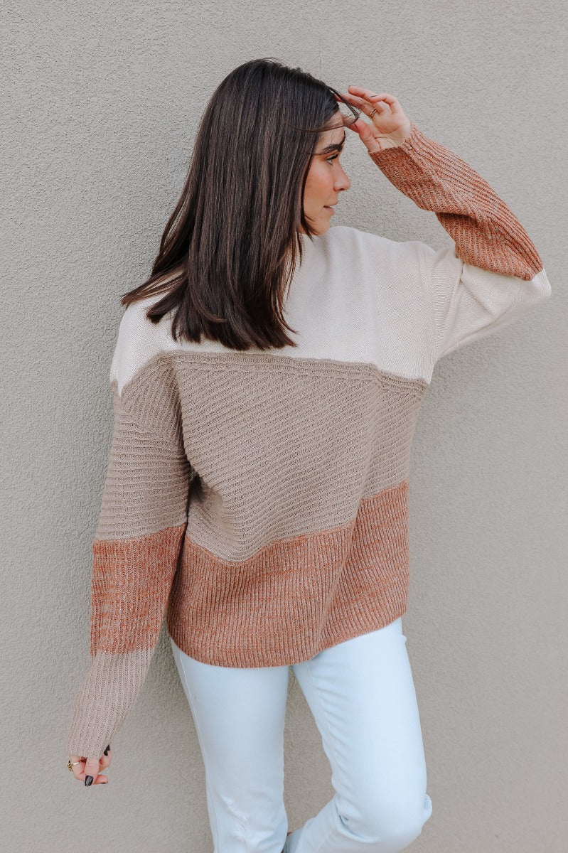Front view of model wearing the Layla Taupe Multi Long Sleeve Sweater which features taupe, cream and rust knit fabric, ribbed details, a round neckline and long sleeves.