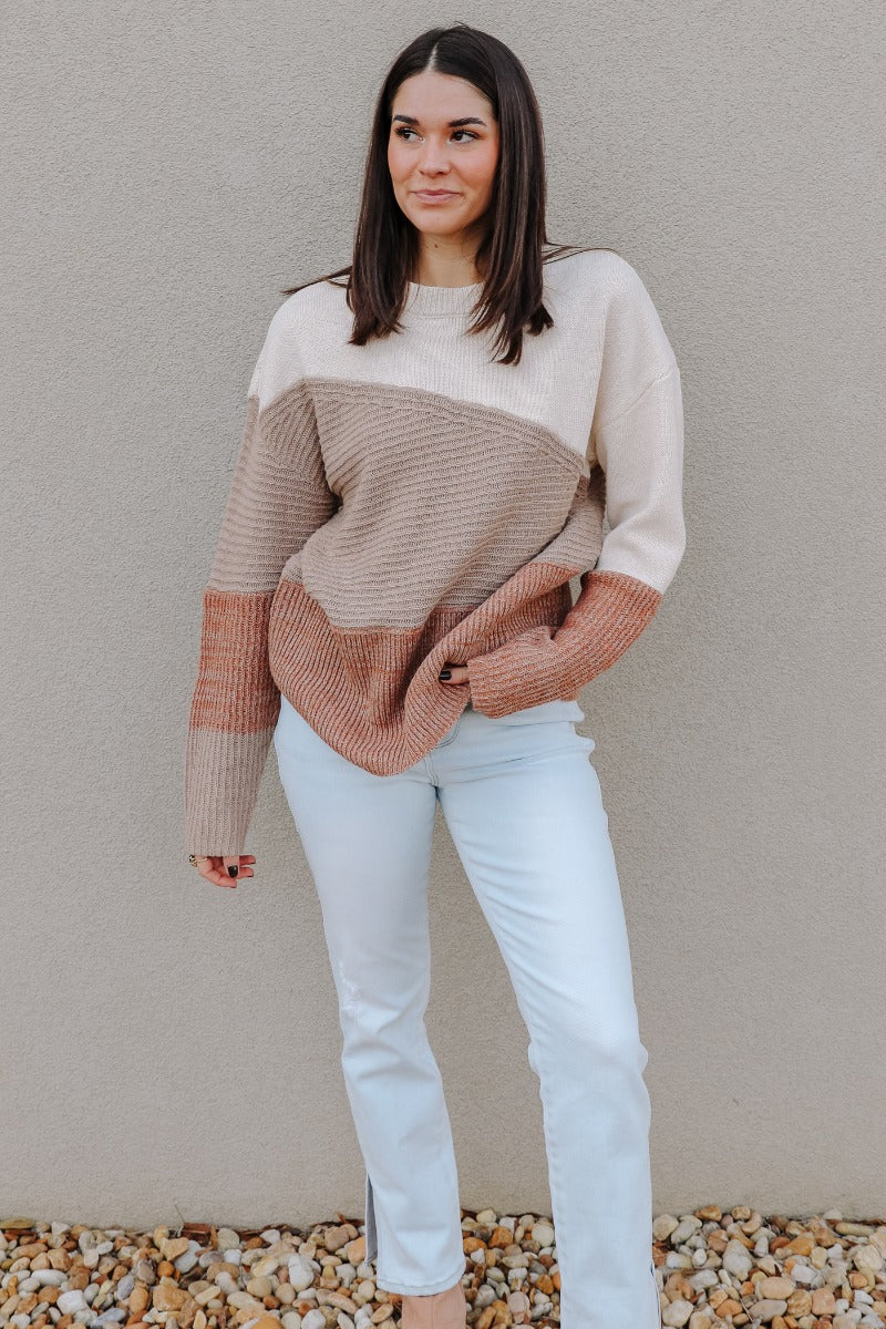 Full body view of model wearing the Layla Taupe Multi Long Sleeve Sweater which features taupe, cream and rust knit fabric, ribbed details, a round neckline and long sleeves.