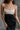 Upper front view of model wearing the Kaliyah Black & Cream Satin Midi Dress that has black, taupe and cream satin fabric, midi length, slits, a colorblock detail, a scoop neck, tie straps, and an open back.