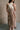 front view of model wearing the Rosalia Cream & Taupe Layered Satin Midi Dress that has cream and taupe satin, midi length, layered pleated details, a halter neck and open back.