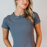 Front view of model wearing the Robin Grey Athletic Short Sleeve Top which features grey athleisure fabric, monochrome stitch details, a scooped neckline, and short sleeves.