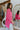 Side view of model wearing the Take My Hand Sweater that has hot pink loose-knit fabric, a high-low hem, a round neck, and 3/4 batwing sleeves with cuffs