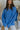 Front view of model wearing the Ocean Eyes Button-Up Top that has blue fabric, a high-low hem, an oversized fit, a button-up front with a collar, front chest pockets, and long sleeves.
