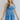 Front view of model wearing the Forget Me Not Babydoll Dress that has blue and light blue organza fabric with a floral pattern, a mini-length hem, a square neck, a back zipper with a hook closure, and short puff sleeves