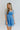 Front view of model wearing the Forget Me Not Babydoll Dress that has blue and light blue organza fabric with a floral pattern, a mini-length hem, a square neck, a back zipper with a hook closure, and short puff sleeves