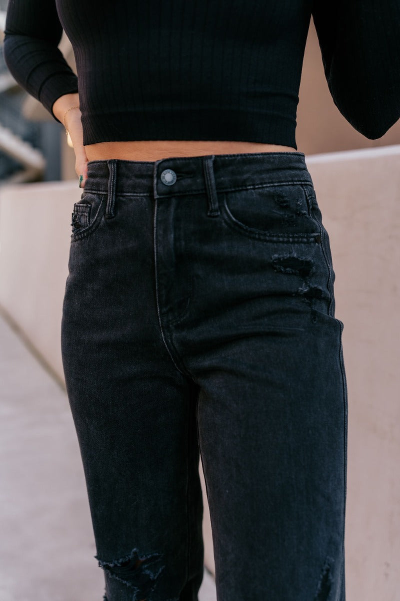 Close up view of model wearing the Judy Blue: Alicia Black Straight Leg Jeans which features washed black denim, two front pockets, two back pockets, front zipper with button closure, belt loops, distressed details, busted knee details and straight pant l