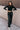 Full body front view of model wearing the Alexis Black Faux Leather Pants which features black faux leather, front zipper with button closure, two front pockets, two back pockets, belt loops and wide pant legs.