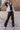 Full body front view of model wearing the Alexis Black Faux Leather Pants which features black faux leather, front zipper with button closure, two front pockets, two back pockets, belt loops and wide pant legs.