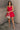 Full body view of model wearing the Avery Red Bow Mini Dress which features crimson red sheen fabric, red lining, mini length, two front pockets, sweetheart neckline, adjustable straps, sleeveless, monochromatic side zipper with hook closure, smocked back