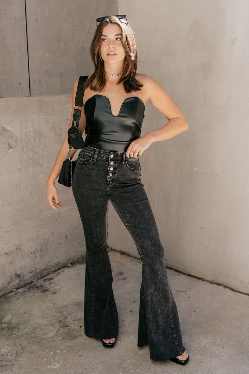 Full body view of model wearing  the Stella Black Faux Leather Strapless Top which features black faux leather, ruched sides, a cropped waist, a strapless sweetheart neckline, and a back zipper.