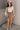 Full body view of model wearing the Journey Mocha Brown Cargo Mini Skirt which features taupe brown textured soft fabric, two fornt cargo pocket with zipper closure, elastic waistband with tie and mini length.