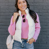 Front view of model wearing the Winnie Iridescent White Puffer Vest that has a zip-up front with a high neck, front pockets, and adjustable drawstrings.