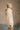 side view of model wearing the Isabella Cream Turtleneck Sweater Dress that has cream cable knit fabric, ribbed trim, mini length, a turtleneck, dropped shoulders, and long balloon sleeves with ribbed cuffs.