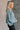 Side view of model wearing the Parker Sea Foam Textured Knit Long Sleeve Sweater which features seafoam textured knit fabric, ribbed hem, round neckline, dropped shoulders and long balloon sleves with cuffs.