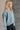 Side view of model wearing the Parker Sea Foam Textured Knit Long Sleeve Sweater which features seafoam textured knit fabric, ribbed hem, round neckline, dropped shoulders and long balloon sleves with cuffs.
