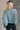 Back view of model wearing the Parker Sea Foam Textured Knit Long Sleeve Sweater which features seafoam textured knit fabric, ribbed hem, round neckline, dropped shoulders and long balloon sleves with cuffs.