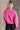 Back view of model wearing the Clara Fuchsia Knit Button Snap Up Long Sleeve Sweater which features hot pink knit fabric, cropped waist, button snap up closure, collared neckline and long sleeves with cuffs.