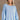 Front view of model wearing the Sadie Light Blue Long Sleeve Sweatshirt which features light blue knit fabric, distressed details, ribbed hem, slits on each side, round neckline, dropped shoulders and long balloon sleeves with cuffs.
