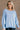 Front view of model wearing the Sadie Light Blue Long Sleeve Sweatshirt which features light blue knit fabric, distressed details, ribbed hem, slits on each side, round neckline, dropped shoulders and long balloon sleeves with cuffs.