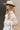 Side view of model wearing the Stephanie Beige & White Checkered Sherpa Shacket which features beige and white textured fabric, checkered print, two front slip pockets, hidden button snaps, collared neckline and long sleeves.