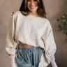 Front view of model wearing the Lyla Cream Long Sleeve Sweatshirt which features washed black knit fabric, a ribbed hem with slight slits on each side, raw hem details, a round ribbed neckline, dropped shoulders and long balloon sleeves with ribbed cuffs.