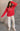 Full body view of model wearing the Merry Red Ribbed Long Sleeve Sweater which features red and light red ribbed fabric, thick hem, a round neckline, a graphic that says "MERRY" in white outline, dropped shoulders, and long sleeves with ribbed cuffs.