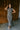 Full body front view of model wearing the Alianna Silver Shimmer Cowl Neck Midi Dress that has grey and silver shimmer fabric, midi length, ruched side details, a slit on the side, a slight cowl high neckline, and a sleeveless design.