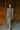 Full body front view of model wearing the Alianna Silver Shimmer Cowl Neck Midi Dress that has grey and silver shimmer fabric, midi length, ruched side details, a slit on the side, a slight cowl high neckline, and a sleeveless design.