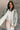 Front view of model wearing the Fairbanks Sage Puffer Long Sleeve Jacket which features light sage nylon puffer fabric, two front slit pockets, light sage lining, front zipper closure, high neckline, back monochrome drawstring, cropped waist and long slee