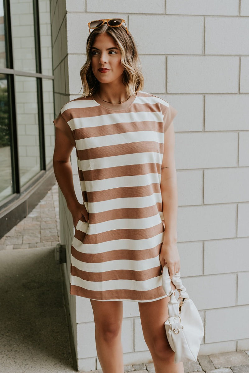Front view of model wearing the Esme Mocha & Cream Striped Dress which features mocha and cream ribbed fabric, striped pattern, mini length, two side pockets, round neckline and short sleeves.