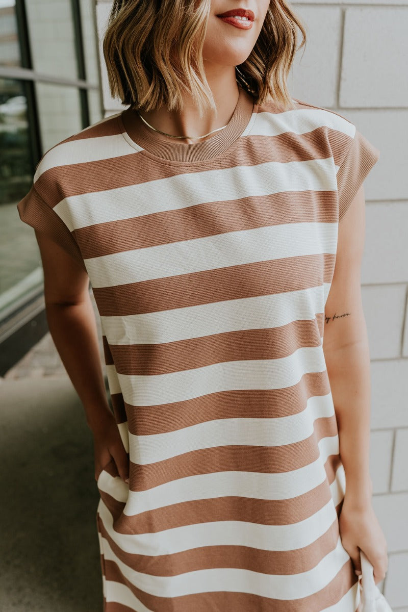 Close up view of model wearing the Esme Mocha & Cream Striped Dress which features mocha and cream ribbed fabric, striped pattern, mini length, two side pockets, round neckline and short sleeves.