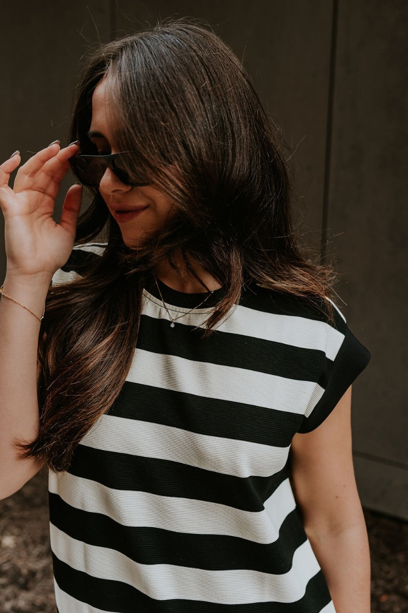 Close up view of model wearing the Esme Black & Cream Striped Dress which features black and cream ribbed fabric, striped pattern, mini length, two side pockets, round neckline and short sleeves.