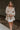 Front view of model wearing the Stella Beige Long Sleeve Mini Dress which features beige lightweight fabric, mini length, flared skirt, beige lining, sweetheart neckline, ruffle details, long sleeves with elastic wrists and smocked back.