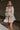 Front view of model wearing the Stella Beige Long Sleeve Mini Dress which features beige lightweight fabric, mini length, flared skirt, beige lining, sweetheart neckline, ruffle details, long sleeves with elastic wrists and smocked back.