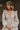 Close up view of model wearing the Stella Beige Long Sleeve Mini Dress which features beige lightweight fabric, mini length, flared skirt, beige lining, sweetheart neckline, ruffle details, long sleeves with elastic wrists and smocked back.