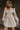 Front view of model wearing the Stella Beige Long Sleeve Mini Dress which features beige lightweight fabric, mini length, flared skirt, beige lining, sweetheart neckline, ruffle details, long sleeves with elastic wrists and smocked back.