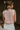 Back view of model wearing the Sophia Pink & White Sleeveless Sweater which features pink and white knit fabric, mini geometric pattern, white ribbed hem, round neckline and sleeveless.