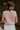 Back view of model wearing the Sophia Pink & White Sleeveless Sweater which features pink and white knit fabric, mini geometric pattern, white ribbed hem, round neckline and sleeveless.