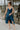Full body front view of mode wearing the Valerie Teal Sleeveless Ruffle Midi Dress that has teal knit fabric, a ruffle hem, a front slit, a v neck, spaghetti straps, and a back zipper with a hook closure.