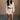 Full body front view of model wearing the Adley Cream Cable Knit Sweater Dress that has a thick cable knit design, ribbed hem, mini length, a round neck, and long balloon sleeves. Worn with belt.
