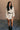 Full body front view of model wearing the Adley Cream Cable Knit Sweater Dress that has a thick cable knit design, ribbed hem, mini length, a round neck, and long balloon sleeves. Worn with belt.