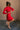 Full body side view of model wearing the Melina Red Turtleneck Sweater Dress that has red ribbed knit fabric, a flared skirt, mini length, a turtleneck neckline, and long sleeves.