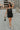 Full body view of model wearing the Brielle Black Sequin Fringe Mini Dress which features black sheer fabric, black lining, mini length, black sequin fringe details, scooped neckline, adjustable straps, sleeveless and monochrome back zippper with hook clo